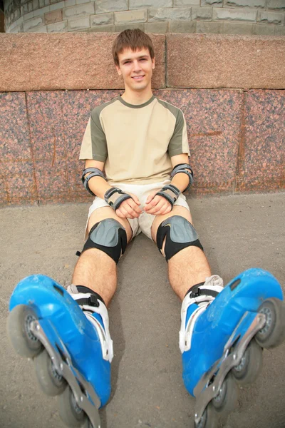 Sitting guy in rollerblades — Stock Photo, Image