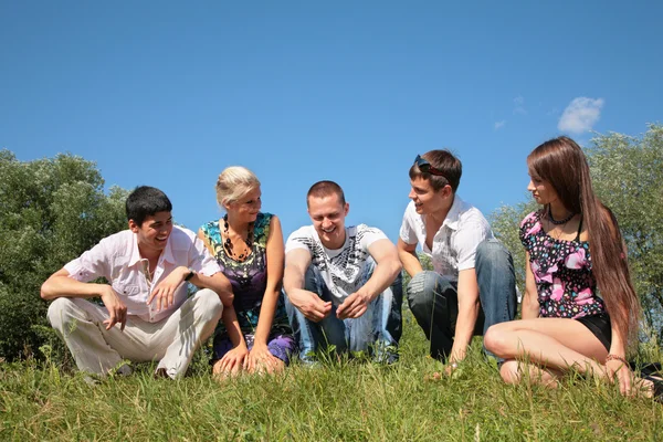 Grupa przyjaciół siedzieć na trawie w okresie letnim — Zdjęcie stockowe