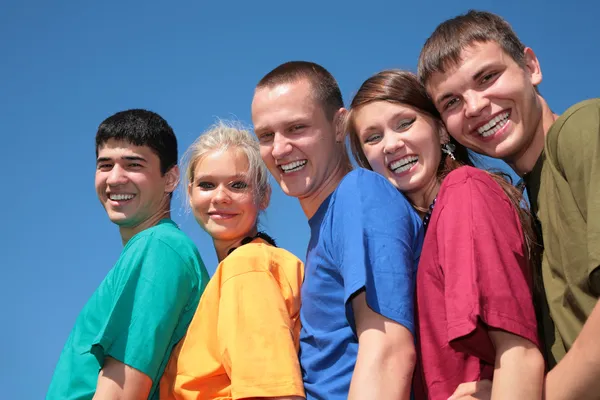 Group of friends in multicolor shirts on sky background — Stock Photo, Image