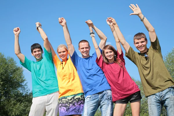 Grupo de amigos em camisas multicoloridas com mãos levantadas — Fotografia de Stock