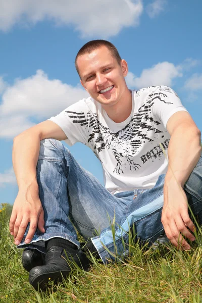 Genç adam çimlerde oturuyor — Stok fotoğraf