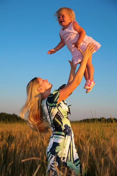 Mother raises child on hands in wheaten field — Stock Photo, Image