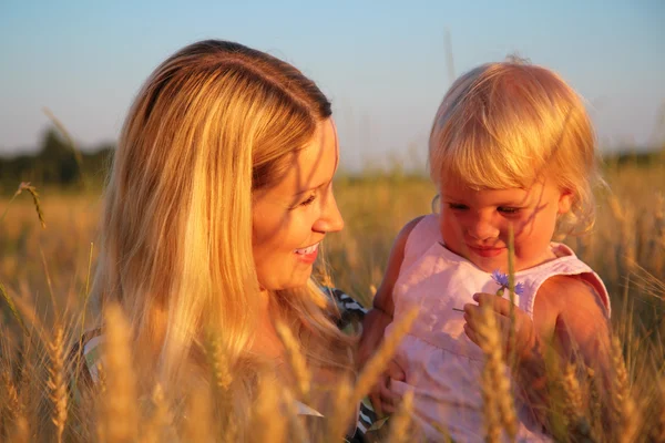 Mother with child sit in wheaten field — Stock Photo, Image