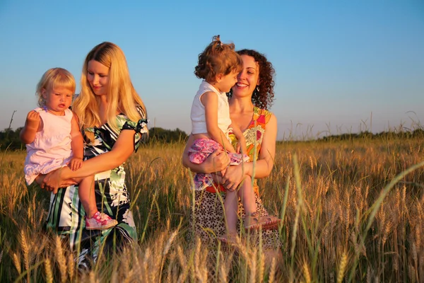 Two mothers with children on wheaten field — Stock Photo, Image