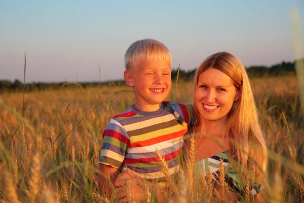 Mother and son sit on wheaten field — Stock Photo, Image
