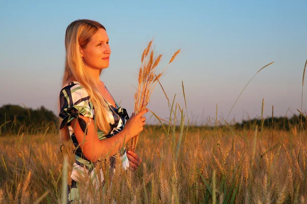 Young woman with earns on weaten field — Stock Photo, Image