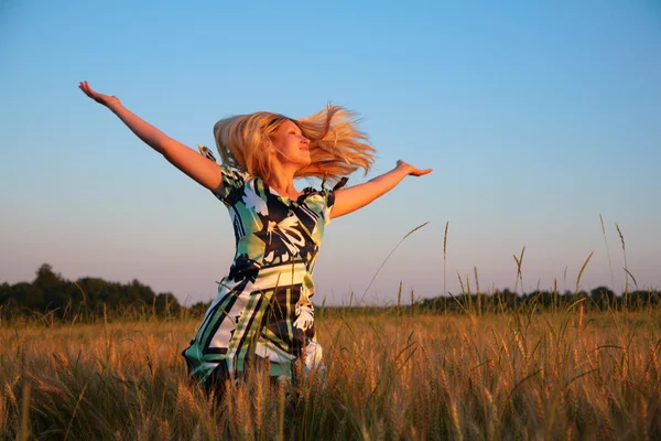 Menina com as mãos levantadas e cabelo voador no campo de trigo — Fotografia de Stock