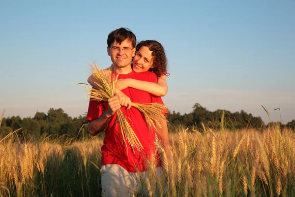 Jeune femme embrasse l'homme derrière sur un champ de blé — Photo
