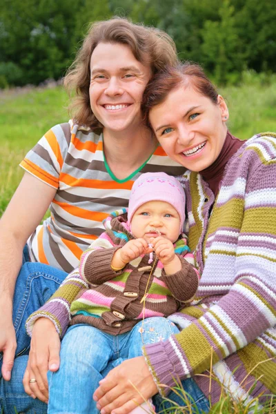 Matka, dítě a otce sedět na trávě — Stock fotografie