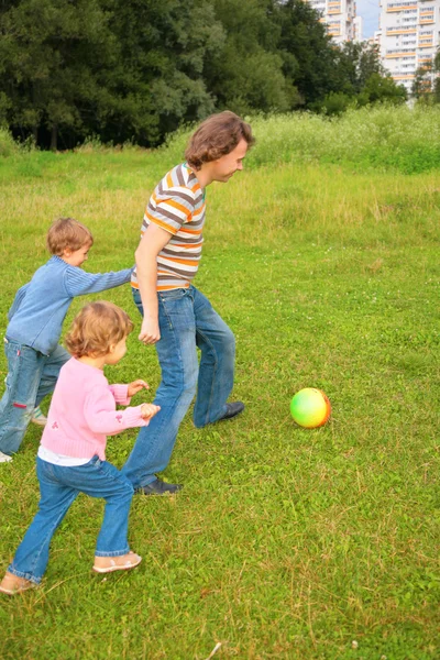 Children play ball with father on grass — Stock Photo, Image