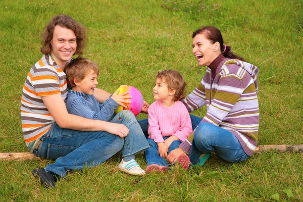 Família senta-se na grama — Fotografia de Stock