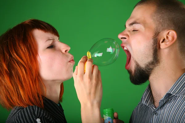 Meisje met rode haren blaast zeepbel in mond aan kerel — Stockfoto