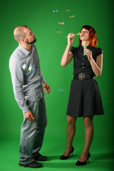 Girl with red hair blows soap bubbles, and guy looks at it — Stock Photo, Image