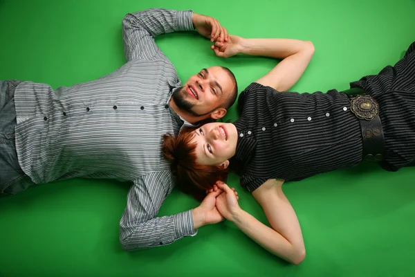 Девушка с рыжими волосами и парень лежат лицом к лицу и держать за руки — стоковое фото