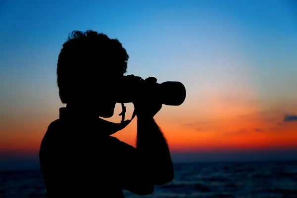 Silhouet van fotograaf aan wal op zonsondergang — Stockfoto