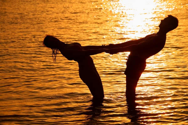 Para trzyma za ręce w morze na zachód słońca — Zdjęcie stockowe