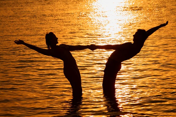 Para trzyma za ręce w morze na zachód słońca — Zdjęcie stockowe