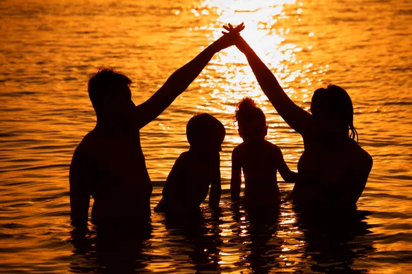 Родители с детьми в море на закате — стоковое фото