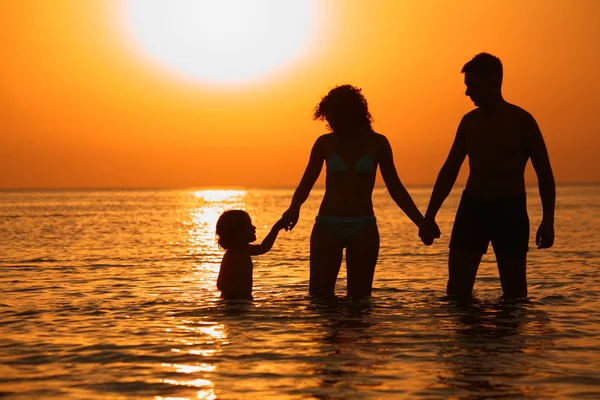 Γονείς με παιδί στη θάλασσα στο ηλιοβασίλεμα — Φωτογραφία Αρχείου