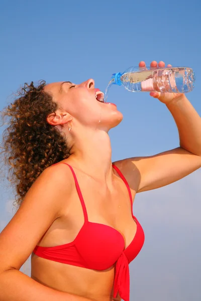 Mädchen im roten Bikini trinkt Wasser — Stockfoto