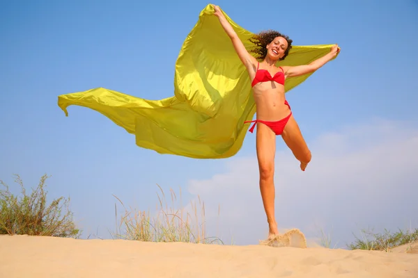 Jong meisje op zand met gele sjaal in handen — Stockfoto