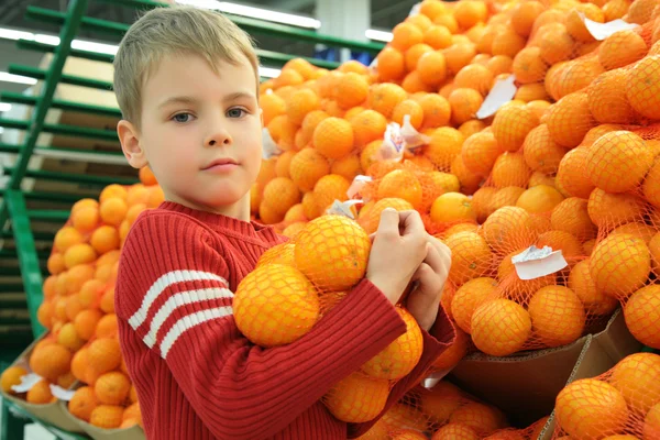 Menino com laranja na loja — Fotografia de Stock