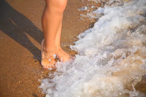 Beine in der Welle auf Sand — Stockfoto