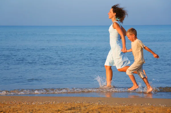 Mãe com filho correndo na borda do mar — Fotografia de Stock
