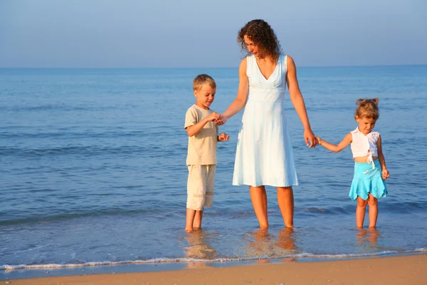Madre con los niños de pie en el agua al borde del mar —  Fotos de Stock