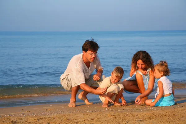 Os pais brincam com crianças na areia na borda do mar — Fotografia de Stock