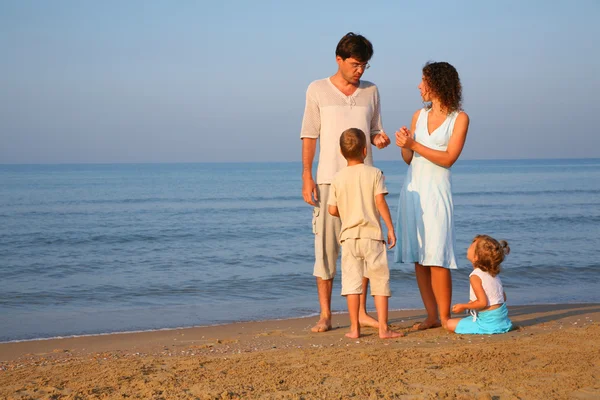 Rodzice z dziećmi, stojący na skraju morza — Zdjęcie stockowe