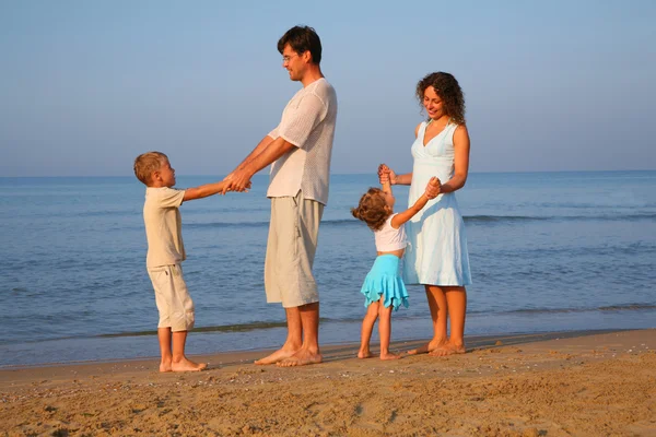 Pais com filhos em pé à beira do mar — Fotografia de Stock