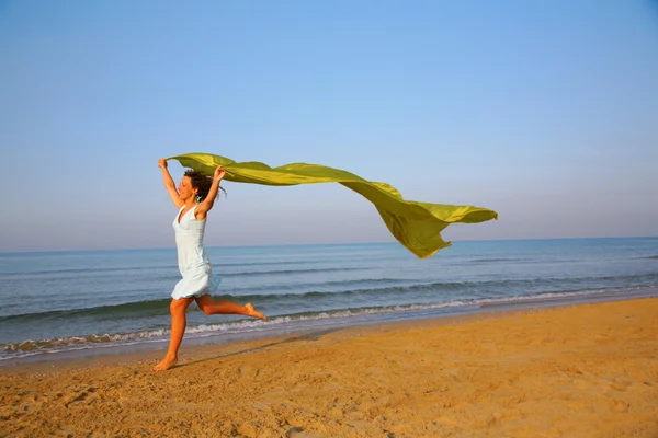 Młoda dziewczyna biegnie na skraju morza żółty szal w ręce — Zdjęcie stockowe