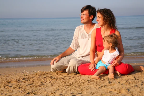 海岸で砂の上に座っている子供を持つ親 — ストック写真