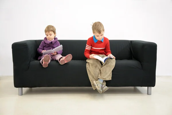 Τα παιδιά κάθονται στον καναπέ και διαβάστε — Φωτογραφία Αρχείου