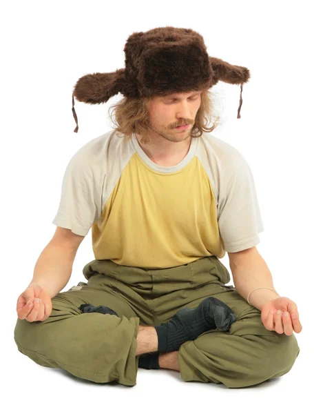 Meditating long-haired Russian man in cap with ear-flaps — Stock Photo, Image