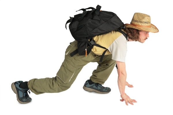 Traveller with backpack in straw hat on all fours