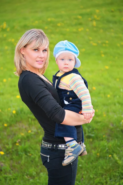 Matka drží dítě v náručí na louce — Stock fotografie