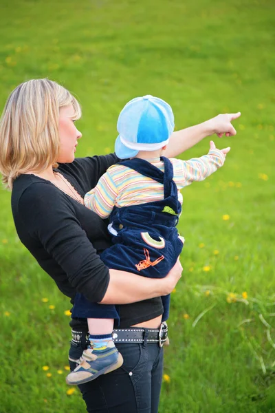 Matka drží dítě v pažích a body na něco — Stock fotografie