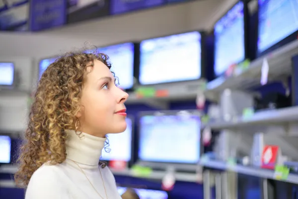 Young woman looks at TVs in shop — Stock Photo, Image