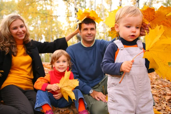 Família com folhas de bordo amarelas em madeira no outono — Fotografia de Stock