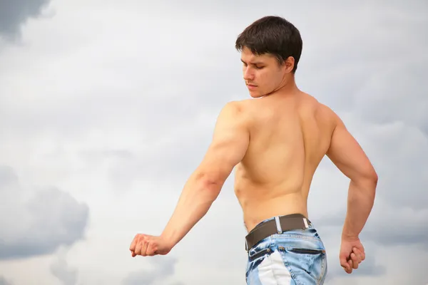 Jeune bodybuilder sur fond nuageux — Photo