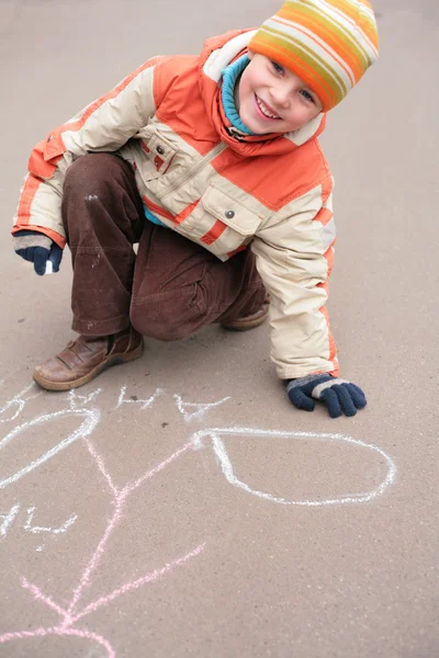 Мальчик рисует мелом на асфальте — стоковое фото