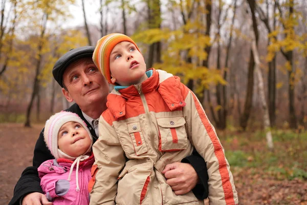 Nagyapja, unokái az őszi erdő felnéz — Stock Fotó