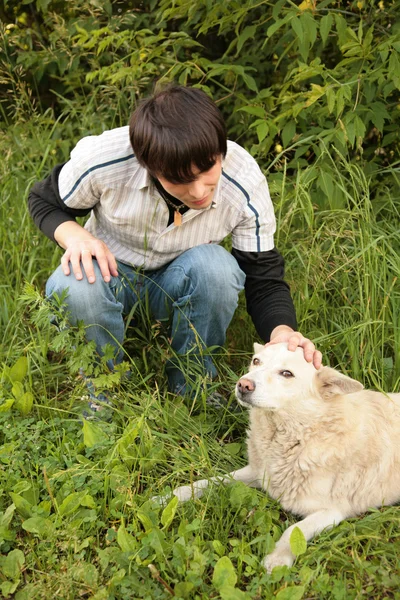 Друзья ласкают вручную собаку в траве — стоковое фото