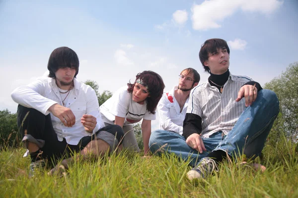 Grupo de amigos se sientan en la hierba — Foto de Stock