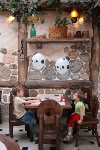 Barnen sitter i café med ballonger — Stockfoto