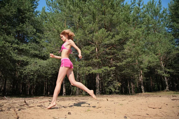Rapariga corre na areia em madeira — Fotografia de Stock