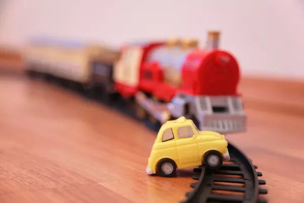 Tren de juguete rojo y coche de juguete amarillo en el ferrocarril — Foto de Stock