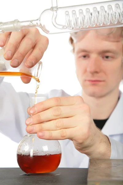 Kemist häller brun vätska i kolv — Stockfoto